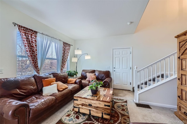 living area featuring light colored carpet, visible vents, baseboards, and stairs