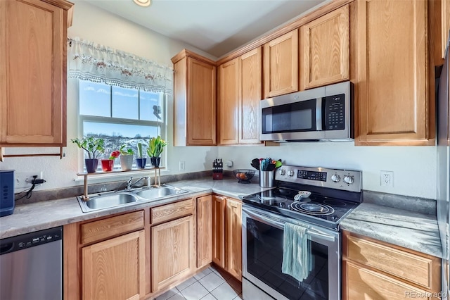 kitchen featuring appliances with stainless steel finishes, light brown cabinets, a sink, and light tile patterned floors