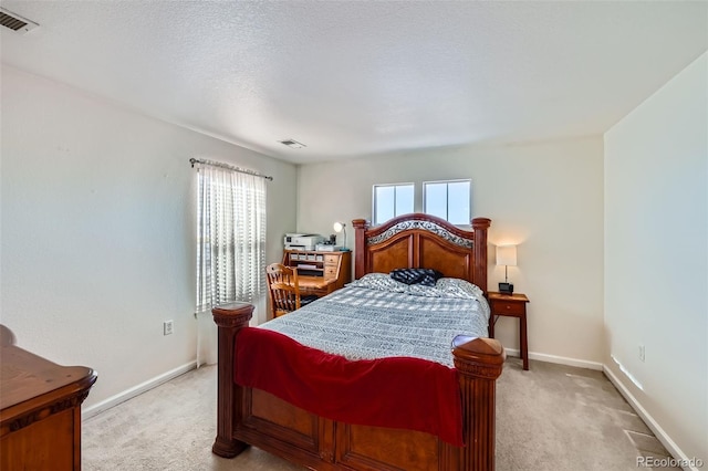 bedroom with baseboards, a textured ceiling, visible vents, and light colored carpet