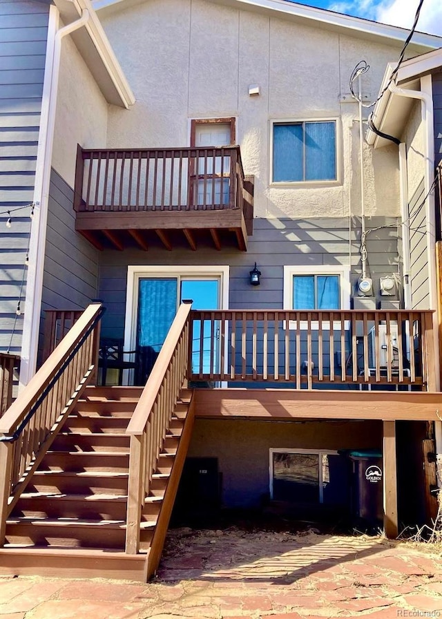 back of property featuring stairs, a balcony, and stucco siding