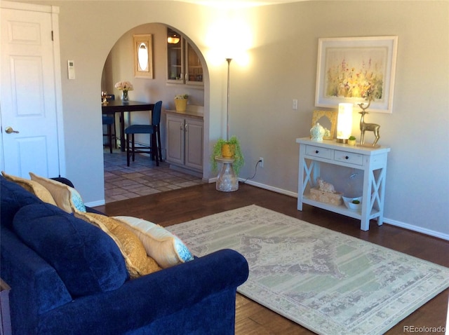 living area featuring baseboards, arched walkways, and wood finished floors