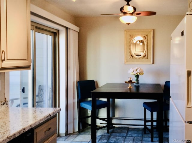 dining area featuring ceiling fan and stone finish flooring