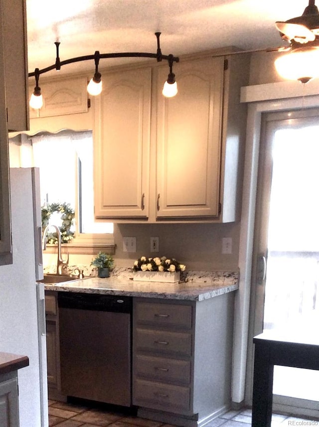 kitchen with stainless steel dishwasher, a sink, and freestanding refrigerator