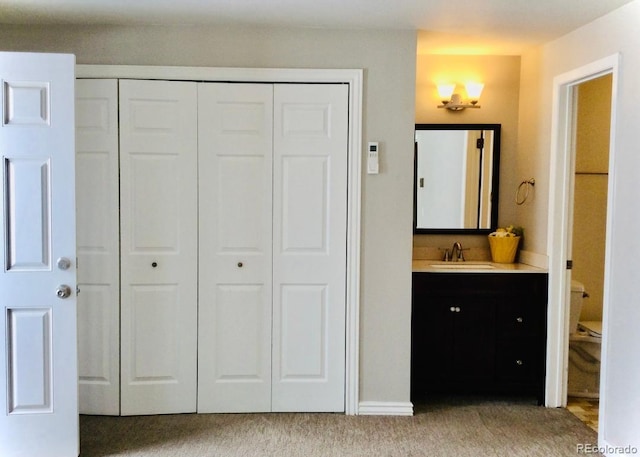 interior space featuring connected bathroom, a closet, light colored carpet, and a sink