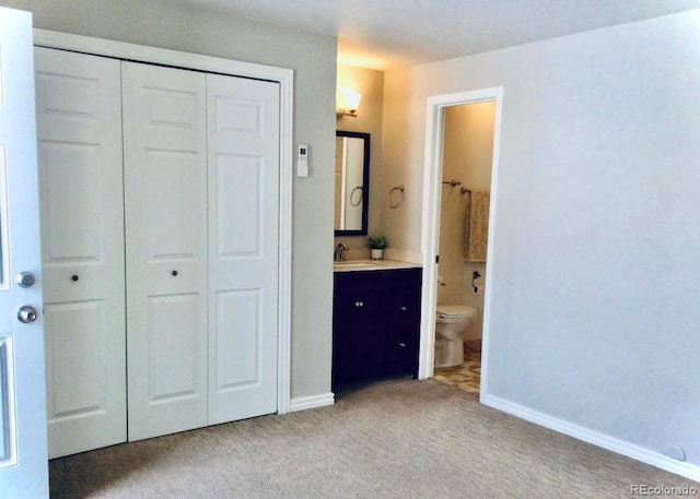 unfurnished bedroom featuring a closet, light carpet, a sink, and baseboards