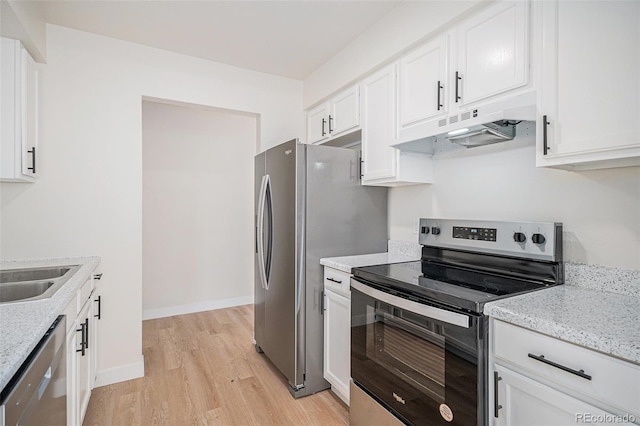 kitchen with stainless steel appliances, white cabinetry, light hardwood / wood-style flooring, and light stone counters