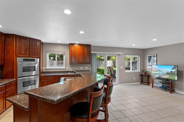 6143 S Ash Cir E, Centennial, CO 80121 - kitchen with double oven, healthy amount of natural light, a breakfast bar, recessed lighting, and light tile patterned floors