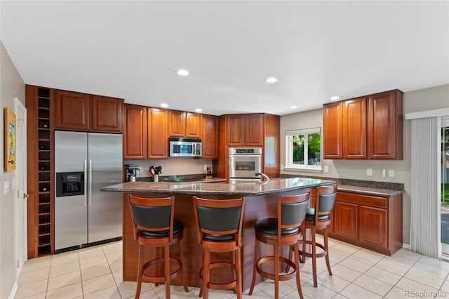 6143 S Ash Cir E, Centennial, CO 80121 - kitchen featuring appliances with stainless steel finishes, a center island, a breakfast bar, light tile patterned floors, and recessed lighting