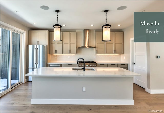 kitchen with wall chimney exhaust hood, sink, high end fridge, and hanging light fixtures