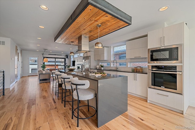 kitchen featuring modern cabinets, island exhaust hood, oven, and built in microwave