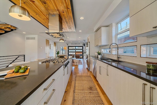 kitchen featuring visible vents, island exhaust hood, stainless steel appliances, light wood-style floors, and a sink