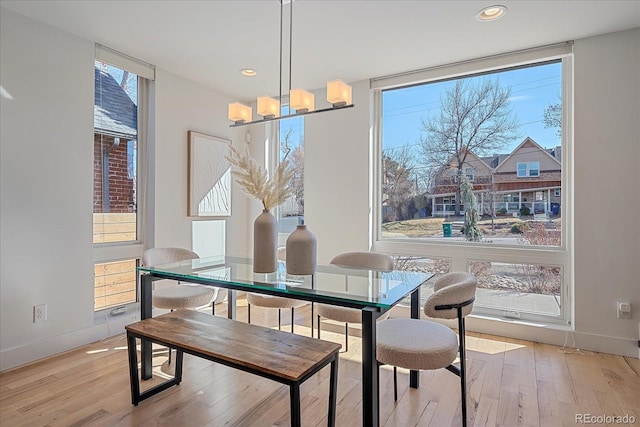 dining area with expansive windows, wood-type flooring, and baseboards