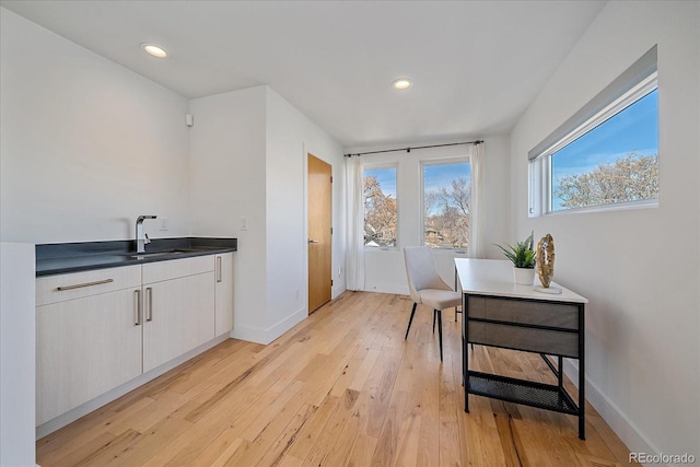 interior space featuring light wood-style floors, baseboards, a sink, and recessed lighting