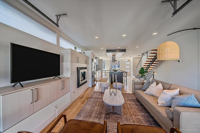 living room featuring a wealth of natural light, stairway, light wood finished floors, and recessed lighting