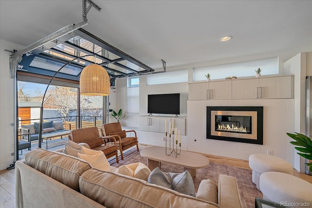 living area with light wood-type flooring, a tile fireplace, a wealth of natural light, and recessed lighting