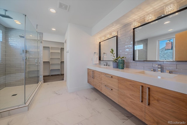 bathroom featuring marble finish floor, tasteful backsplash, a stall shower, a sink, and baseboards