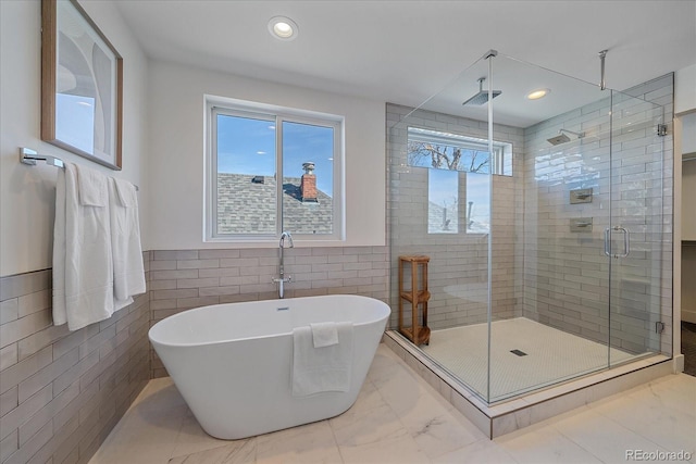 full bathroom featuring marble finish floor, tile walls, recessed lighting, a soaking tub, and a stall shower