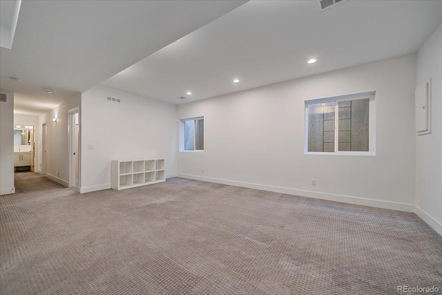 empty room featuring light colored carpet, visible vents, baseboards, and recessed lighting