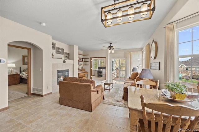 22312 E Plymouth Cir, Aurora, CO 80016 - living area with healthy amount of natural light, a tiled fireplace, arched walkways, and a ceiling fan