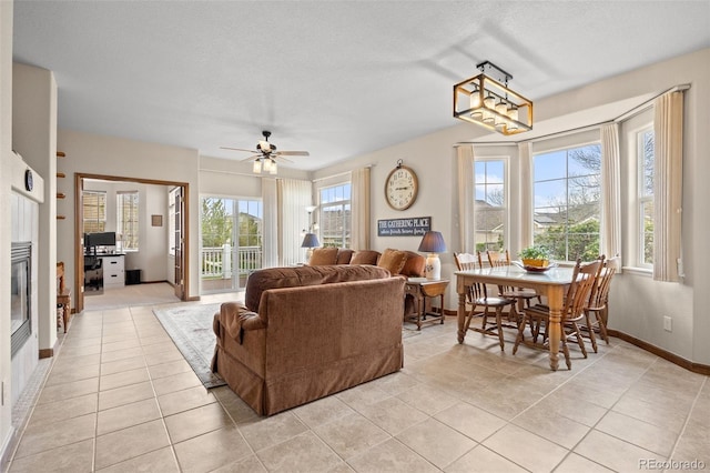 22312 E Plymouth Cir, Aurora, CO 80016 - living room featuring plenty of natural light, light tile patterned flooring, baseboards, and a glass covered fireplace