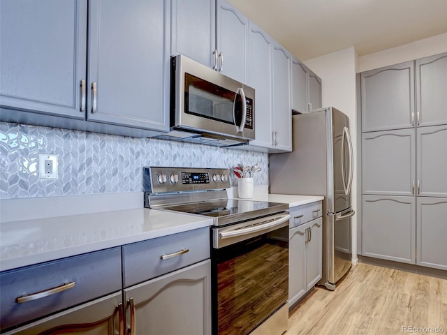 kitchen with tasteful backsplash, light wood-type flooring, and appliances with stainless steel finishes