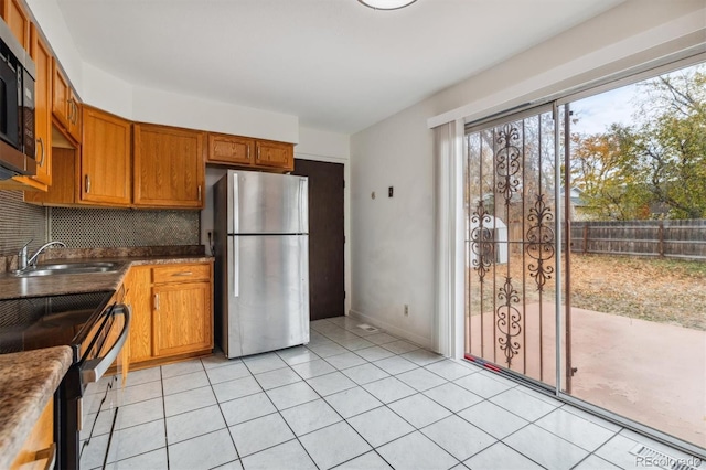 kitchen featuring backsplash, light tile patterned floors, sink, and appliances with stainless steel finishes