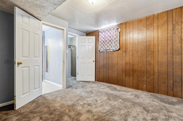 carpeted spare room featuring wooden walls