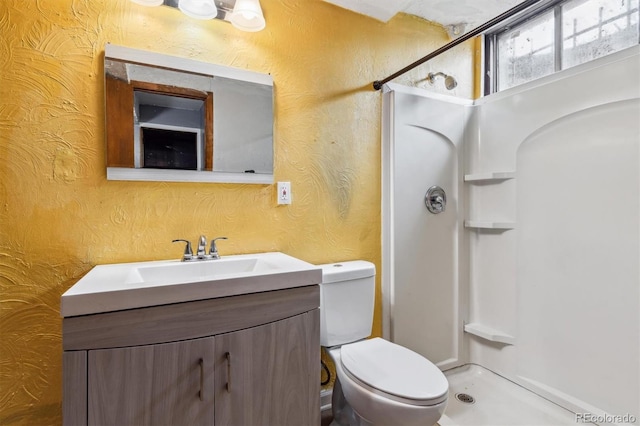 bathroom featuring toilet, a shower, and vanity