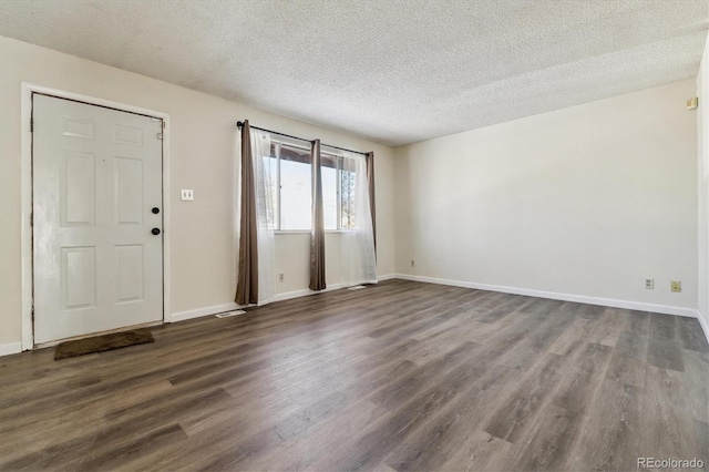 foyer with a textured ceiling, dark wood-style flooring, and baseboards