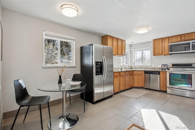 kitchen with light stone countertops, sink, light tile patterned floors, and stainless steel appliances