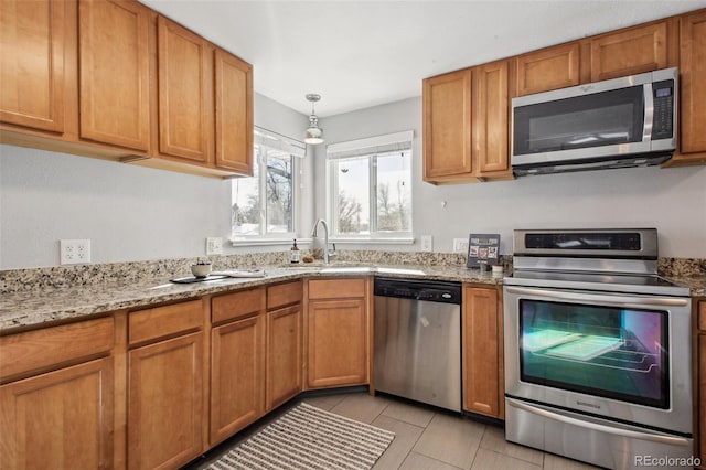 kitchen with pendant lighting, sink, appliances with stainless steel finishes, light tile patterned flooring, and light stone counters