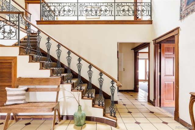 stairs featuring baseboards and a towering ceiling