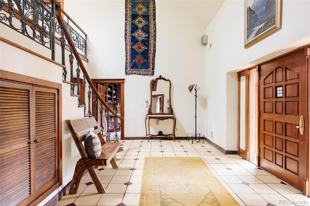 entrance foyer featuring stairway, a high ceiling, and baseboards