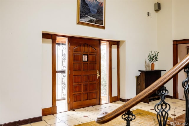 entryway with baseboards, a towering ceiling, and tile patterned flooring