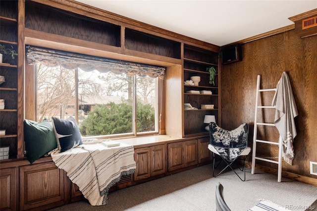 living area with built in features, visible vents, light colored carpet, and wooden walls