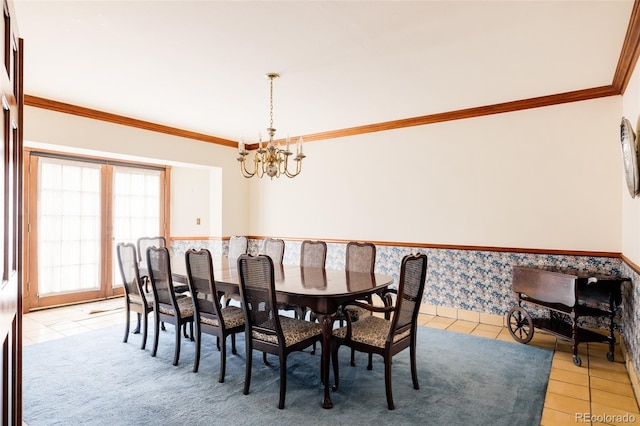 dining area with light tile patterned floors, a wainscoted wall, a chandelier, and crown molding