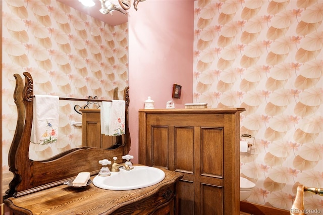 bathroom with wallpapered walls, toilet, and vanity