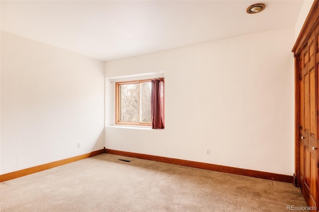 empty room with visible vents, baseboards, and light colored carpet