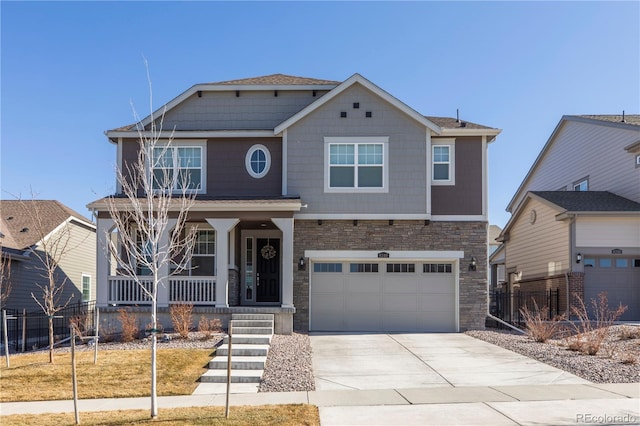 craftsman-style house featuring a porch, concrete driveway, fence, and stone siding