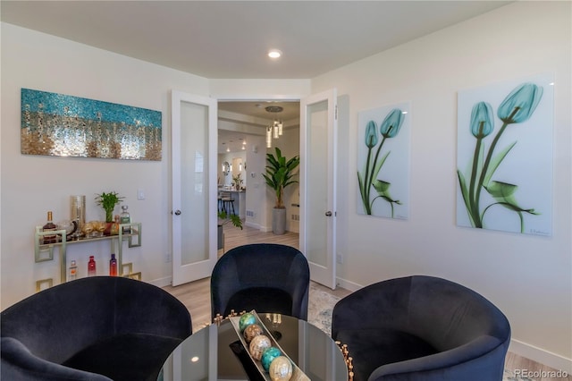 sitting room with light wood finished floors, french doors, visible vents, and baseboards