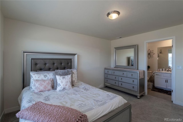 carpeted bedroom featuring ensuite bathroom, visible vents, and baseboards