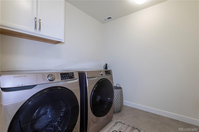 laundry area featuring cabinet space, light tile patterned floors, baseboards, visible vents, and washer and dryer