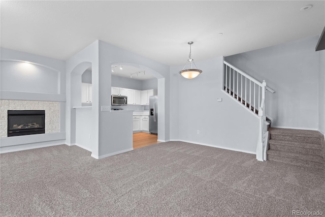 12711 Colorado Blvd Unit 1116, Thornton, CO 80241 - unfurnished living room with light colored carpet, stairs, baseboards, and a glass covered fireplace
