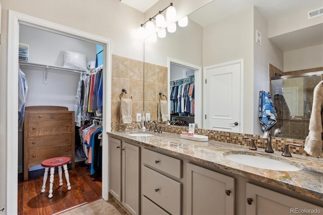 bathroom with vanity, tile patterned flooring, decorative backsplash, and walk in shower