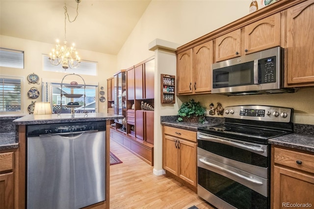 kitchen with stainless steel appliances, light hardwood / wood-style flooring, pendant lighting, a chandelier, and vaulted ceiling