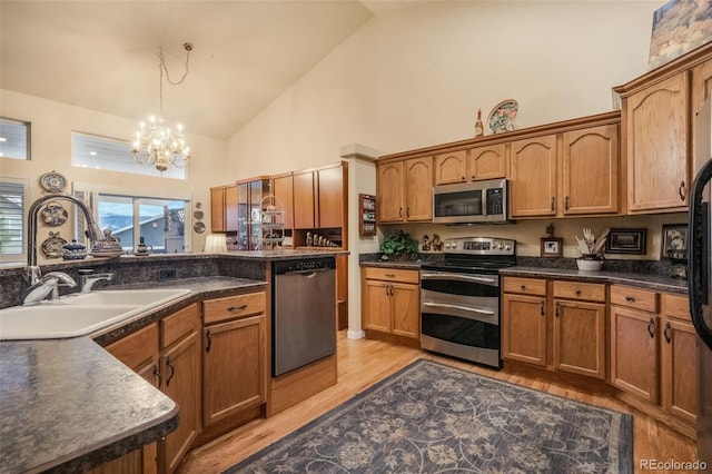 kitchen featuring hanging light fixtures, stainless steel appliances, high vaulted ceiling, a chandelier, and light hardwood / wood-style floors