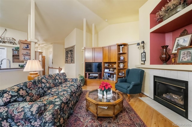 living room featuring light hardwood / wood-style floors, lofted ceiling, and a tile fireplace