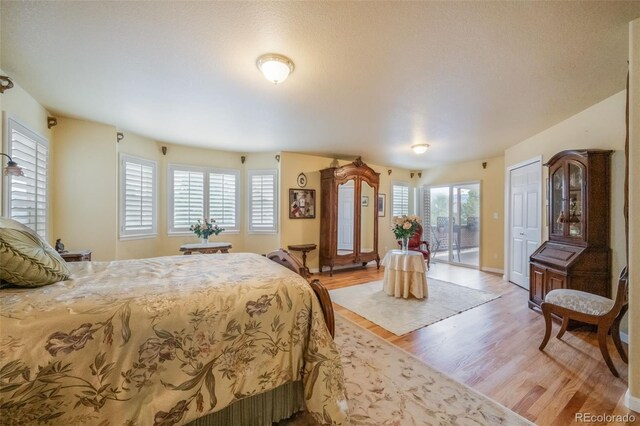 bedroom featuring a textured ceiling, light wood-type flooring, and access to outside