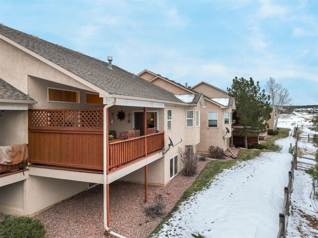 view of snow covered back of property