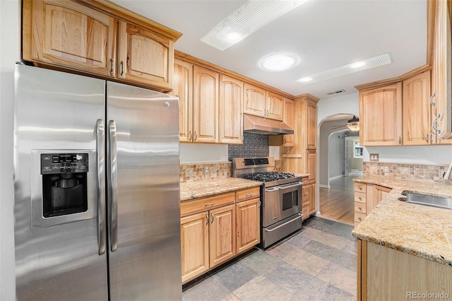 8525 Grandview Ave, Arvada, CO 80002 - kitchen featuring stainless steel appliances, under cabinet range hood, arched walkways, and light stone countertops